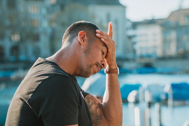 Burnout en hoofdpijn. Jonge man met hoofdpijn en hand op voorhoofd