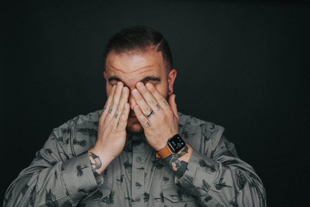 Burn-out ontkennen. Gestreste man slaat handen voor ogen
