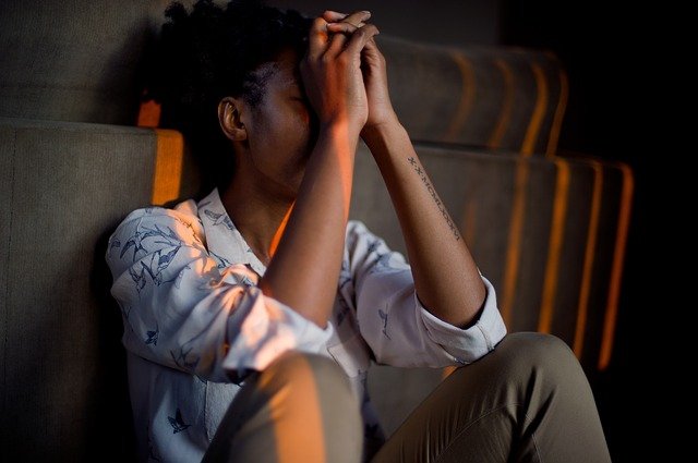 Aanhoudende lichamelijke stressklachten. Vrouw zit somber op de grond.